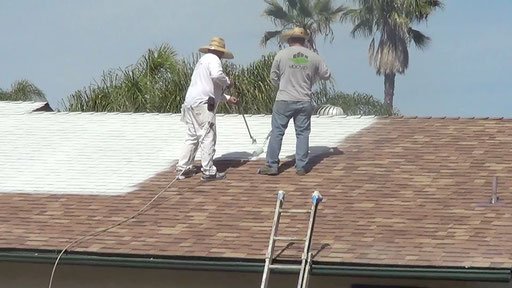 Two workers adding a roof coating for improved roof protection