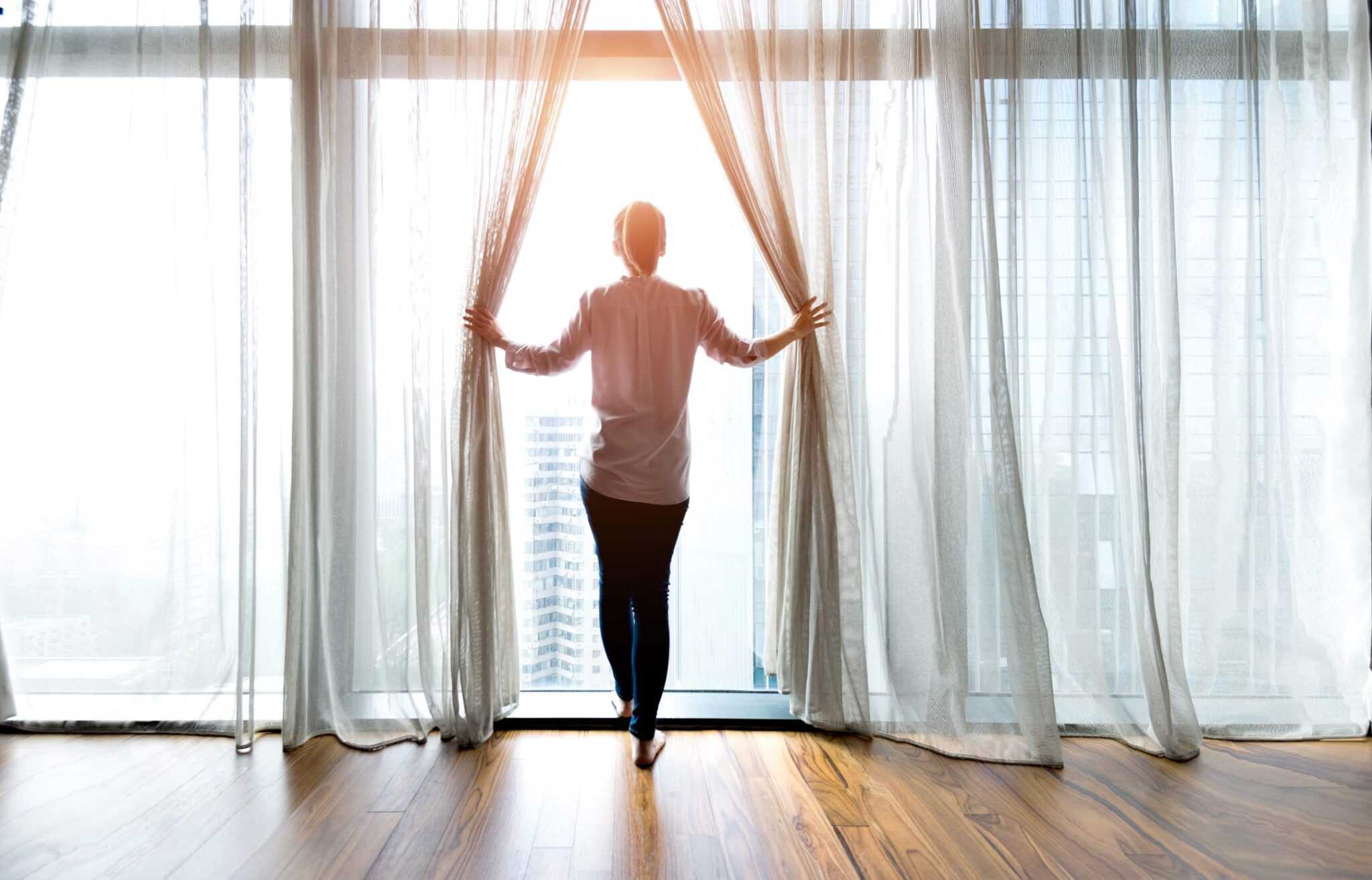 woman opening curtains