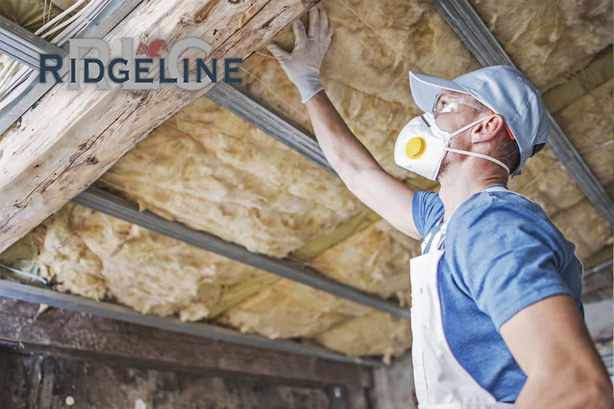 man inspecting insulation in rafters