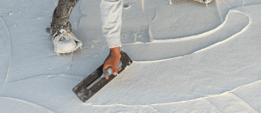 worker wearing spiked shoes smoothing wet pool cement